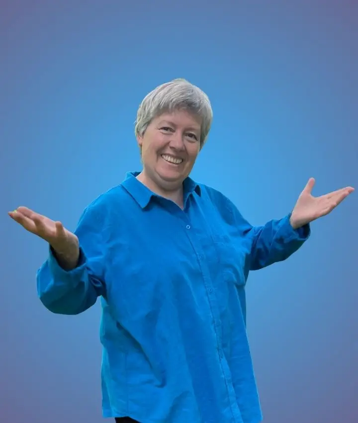 Daniella Wäbs, von der ganzheitlichen Schmerztherapie Hamburg, macht eine einladende Handbewegung mit den Handinnenflächen nach oben gerichtet und lacht in die Kamera.